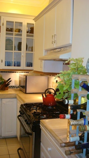 A kitchen with white cabinets, a red kettle, and a wine rack. - DOWNTOWN 4 BEDROOM 2 BATH NEAR CONVENTION CENTER (San Jose)