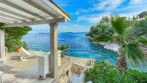 Un espace extérieur abrité comprenant une piscine, des chaises longues et une vue sur la mer.