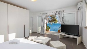 Une chambre moderne avec un grand lit, une télévision et une vue sur la mer.