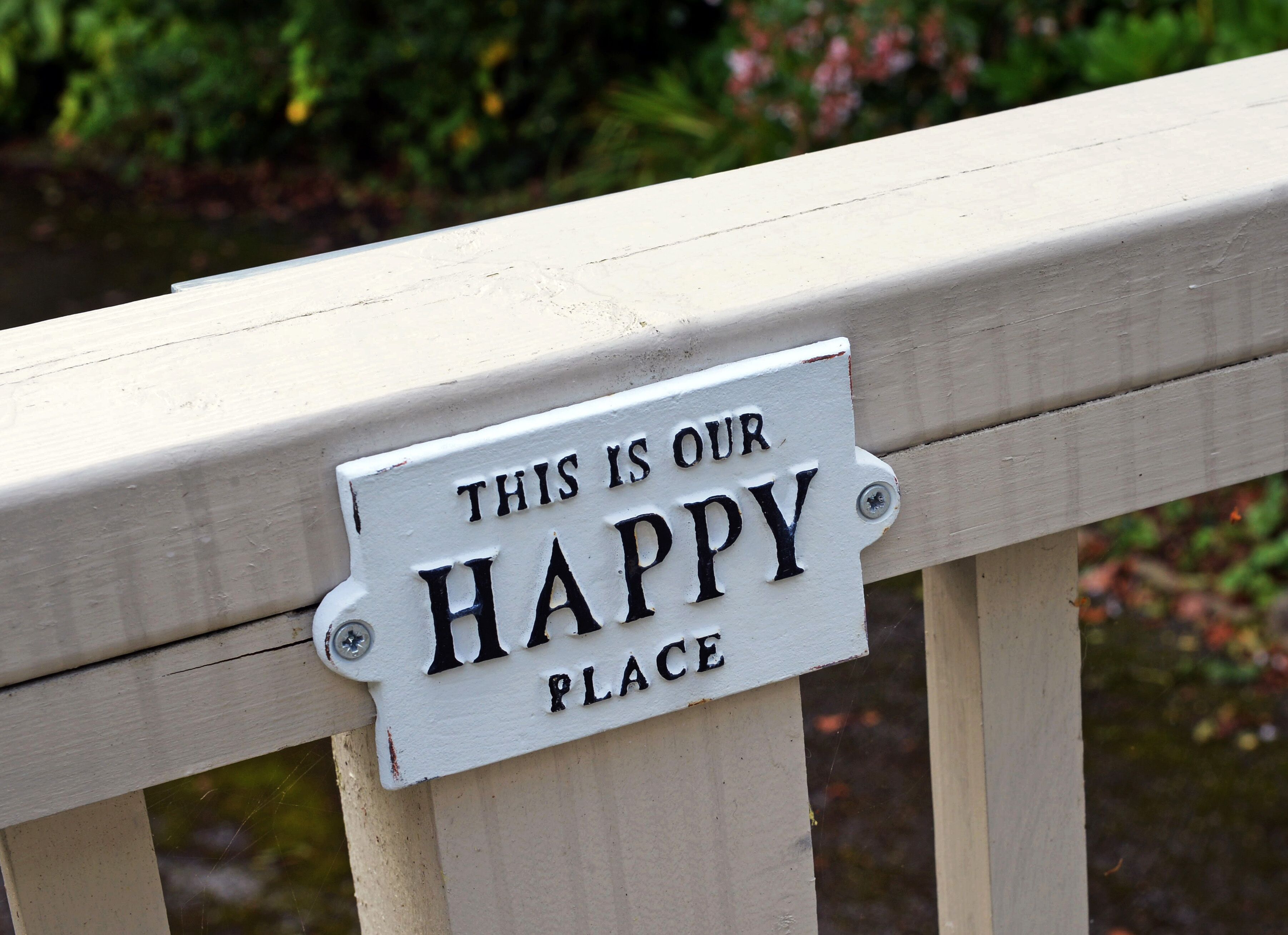 Une plaque blanche avec des lettres noires, fixée sur une rambarde en bois.