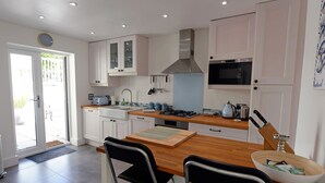 A modern kitchen with white cabinets, a wooden countertop, a gas stove, and a microwave. - Valley Retreat - Peaceful Cottage, Walk to Beach (Saundersfoot)
