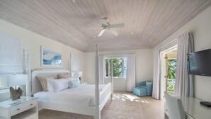 A bedroom with a four-poster bed, a ceiling fan, a TV, and a view of the outdoors.