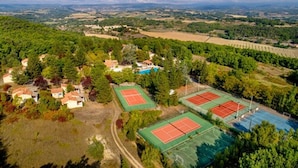 Vue aérienne d’une zone rurale avec plusieurs courts de tennis entourés d’arbres et de maisons.