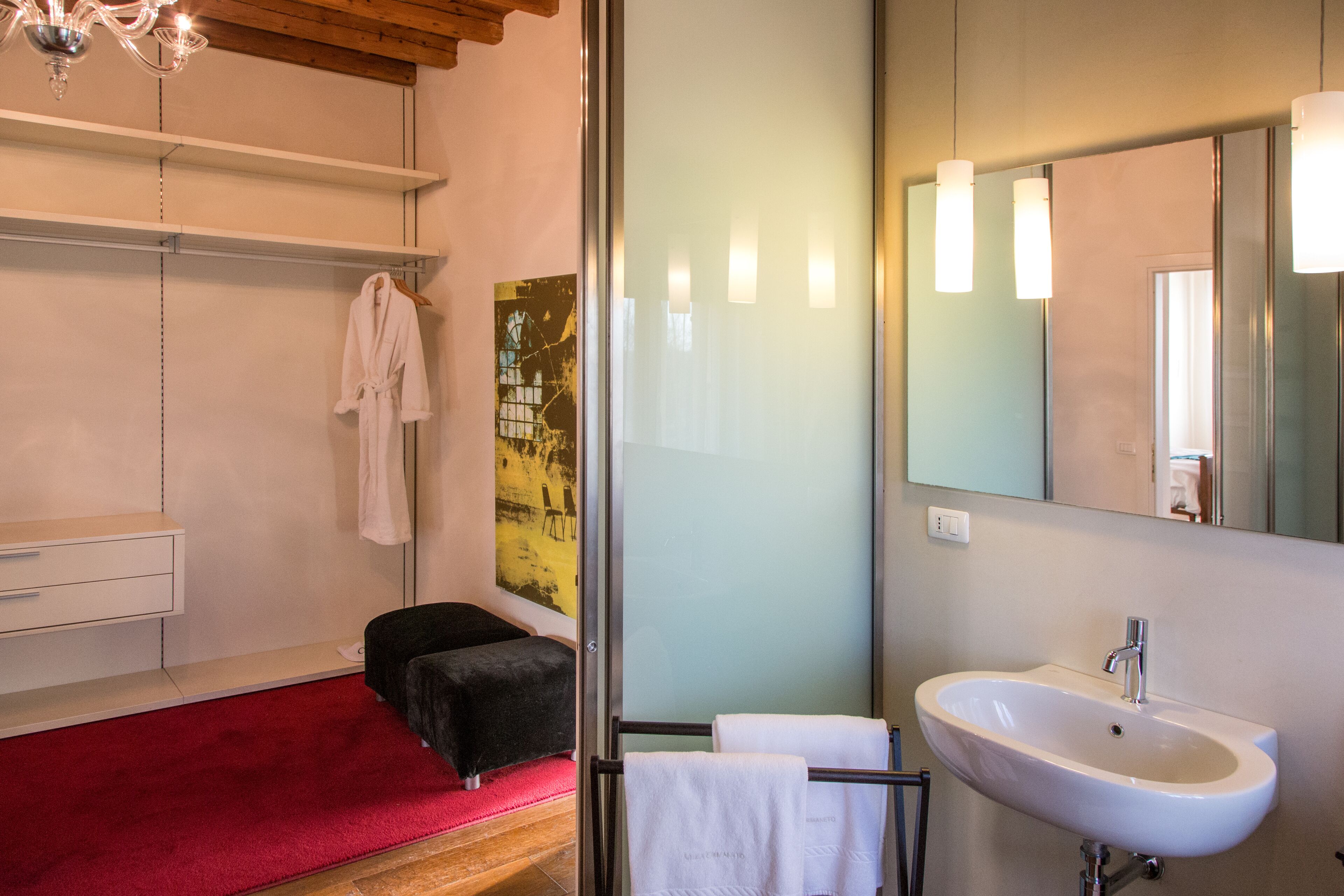 A modern bathroom with a white sink, a large mirror, and a red carpet.