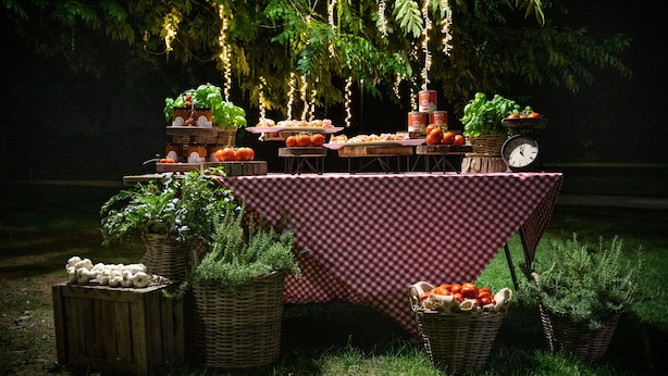 A table set up outdoors with a checkered tablecloth, surrounded by baskets of vegetables and a clock. - Relais Villa Ormaneto (Cerea)