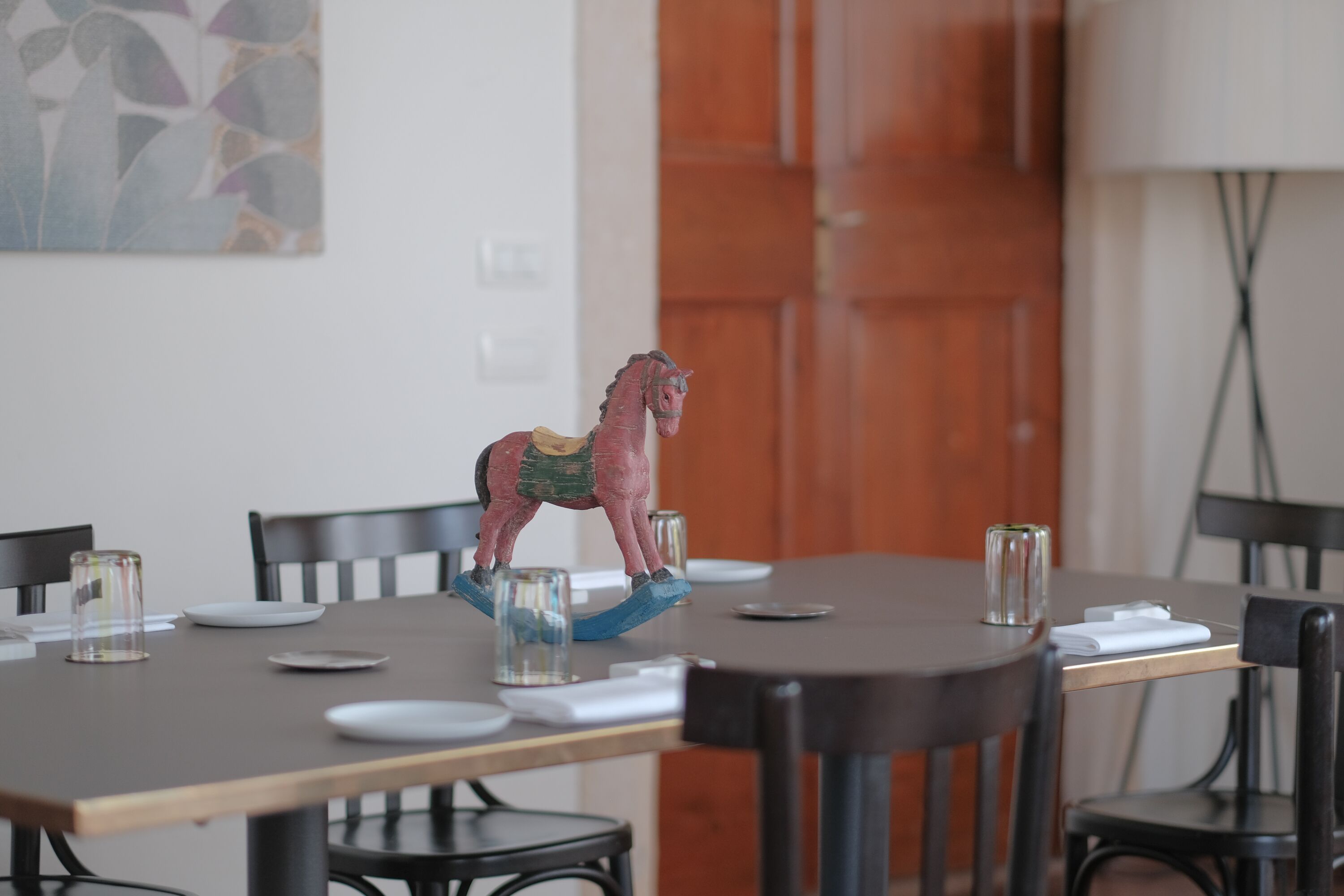 Un tavolo da pranzo con sedie, una statuina decorativa a forma di cavallo e una lampada.