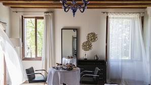 A room with a bed, a table with breakfast items, a dresser, and a chandelier. - Relais Villa Ormaneto (Cerea)