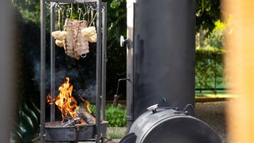 En portabel utomhusgrill med en skorsten, ett metallgaller för att lägga maten på och en synlig eld.