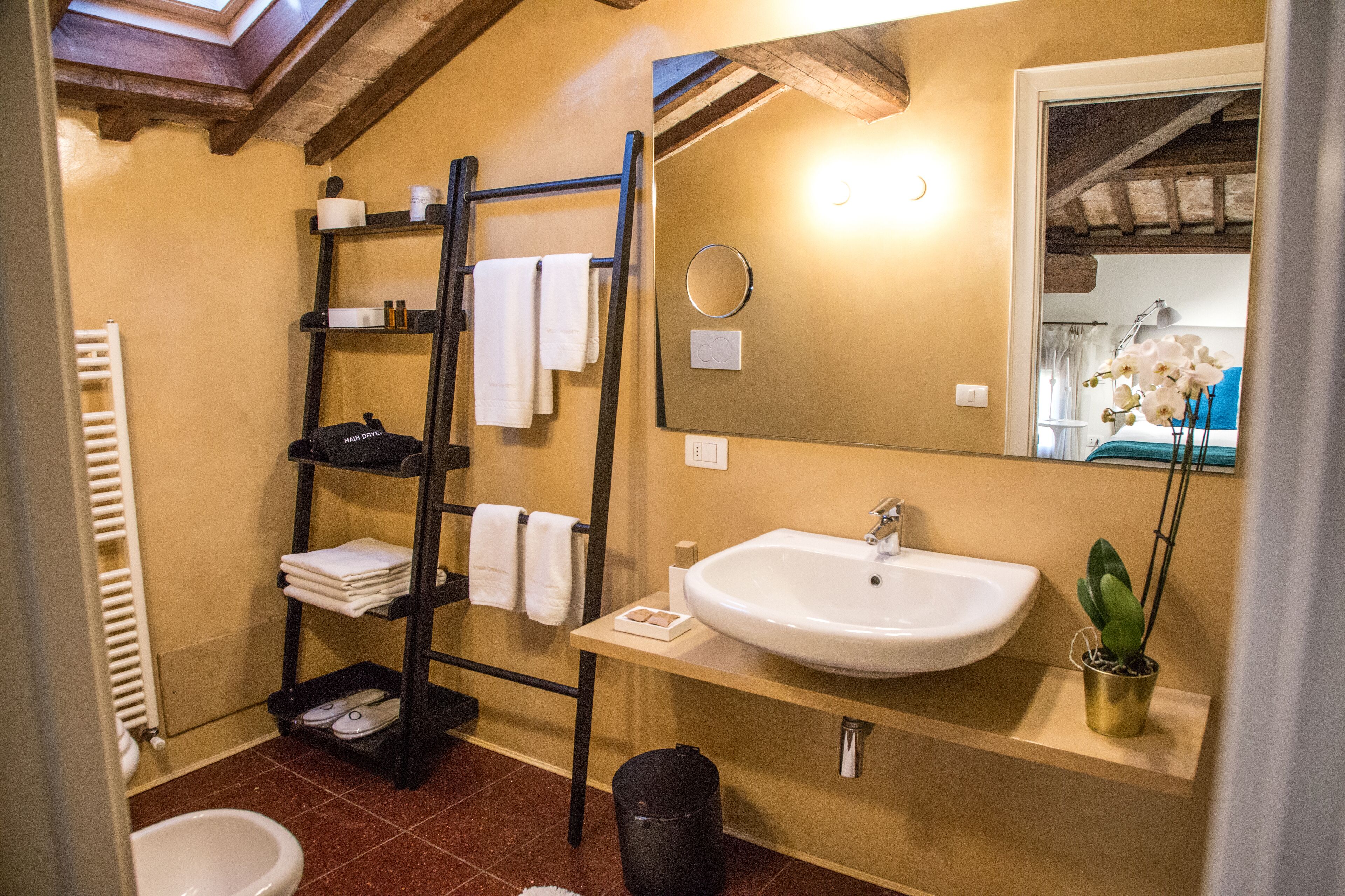 A bathroom with a sink, mirror, towel rack, and a small potted plant.