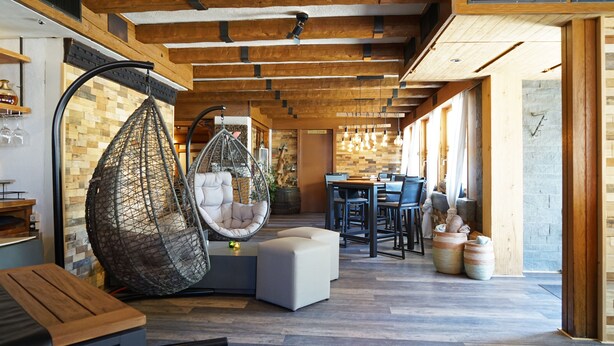 A modern interior with a hanging chair, a dining area, and a wooden ceiling. - Hotel Twing (Hasliberg)