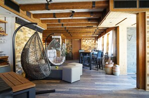 Un interior moderno con un sillón colgante, una zona de comedor y un techo de madera.