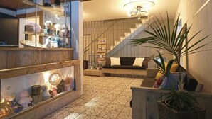 A modern interior with a staircase, a sofa, and a display case with various items. - Hotel Twing (Hasliberg)