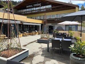 A hotel named 'Hotel Twing' with outdoor seating and a garden area. - Hotel Twing (Hasliberg)