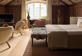 A bedroom with a wooden ceiling, a large bed, a desk, a chair, and a TV.