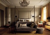 A four-poster bed with a canopy, a sofa, a round ottoman, and a chair in a room with a chandelier, a fireplace, and a large window with curtains.