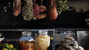 A kitchen with hanging meats, preserved foods, and a bottle of wine. - Ett Hem (Stockholm)