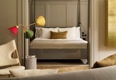 A modern bedroom with a bunk bed, a bedside table, a lamp, and a chair.