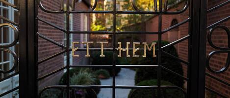 A wrought iron gate with the inscription "ETI MEM" in the center.
