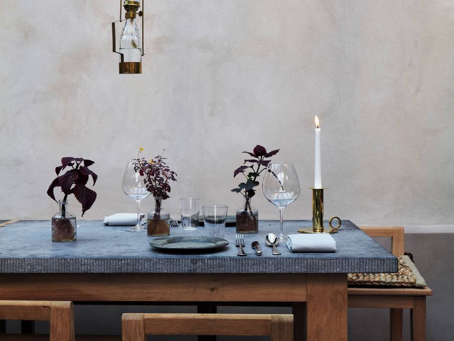 A dining table set with glassware, plates, and candles.