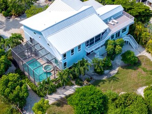 A two-story house with a swimming pool, surrounded by tropical vegetation.