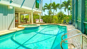 Una piscina con hidromasaje, sillas de descanso y un área de patio cubierta.