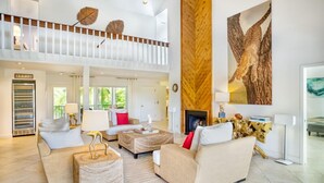 Un salón comedor amplio con techo alto, chimenea y un gran cuadro de un leopardo.