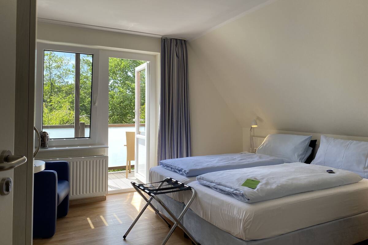 A hotel room with a bed, a desk, and a view of the outdoors.