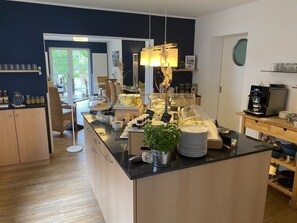 A modern kitchen with a central island, wooden cabinets, and a coffee machine. - Hotel garni DünenNest (St. Peter-Ording)