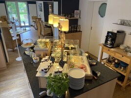 Ein Bereich mit einem Buffet, verschiedenen Speisen, einer Kaffeemaschine und einer Pflanze.