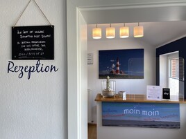 Ein Empfangsbereich mit einer Kreidetafel, einem Willkommensschild und einem Gemälde eines Leuchtturms.