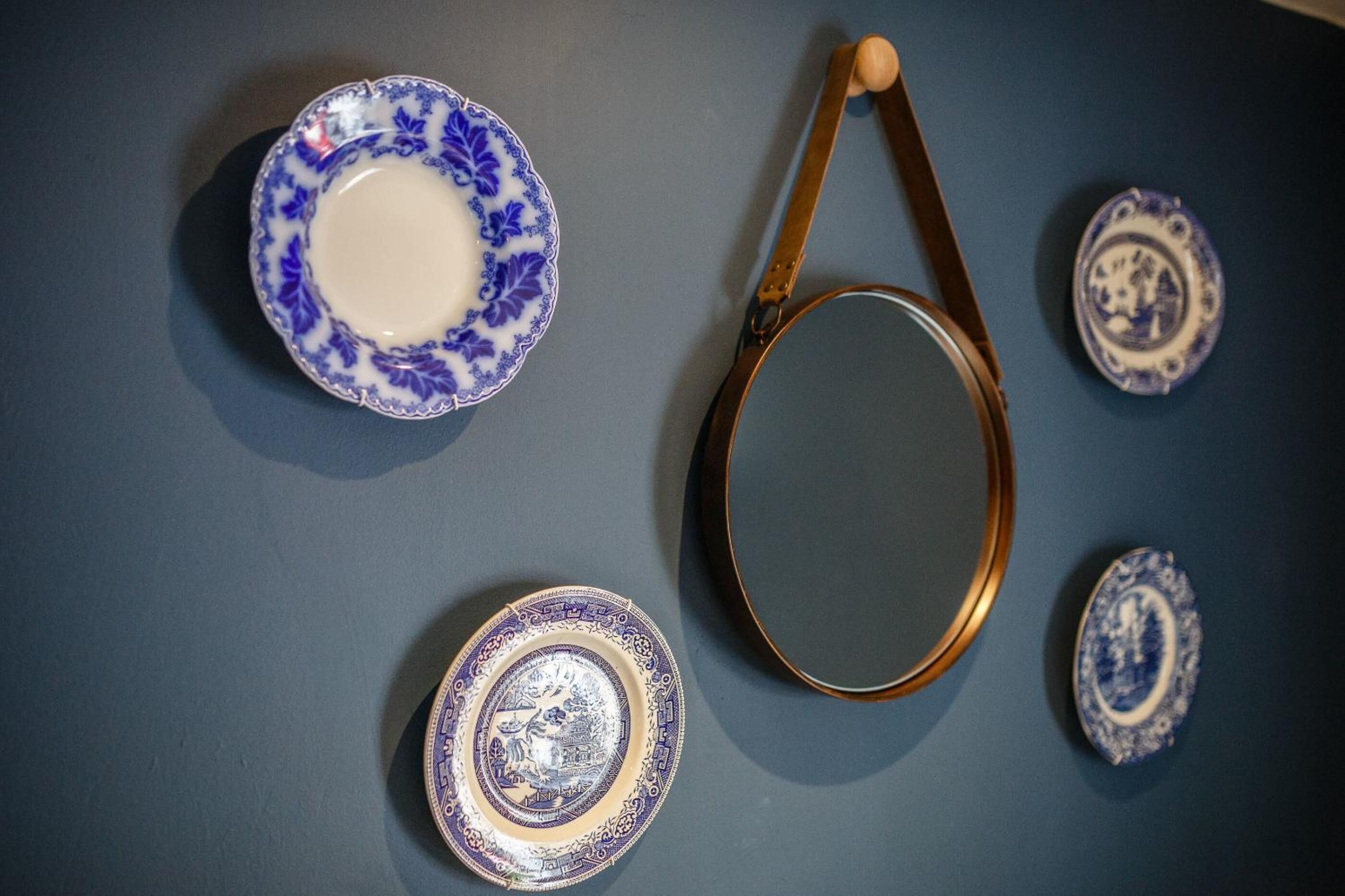A blue wall with four ceramic plates and a metal tray.