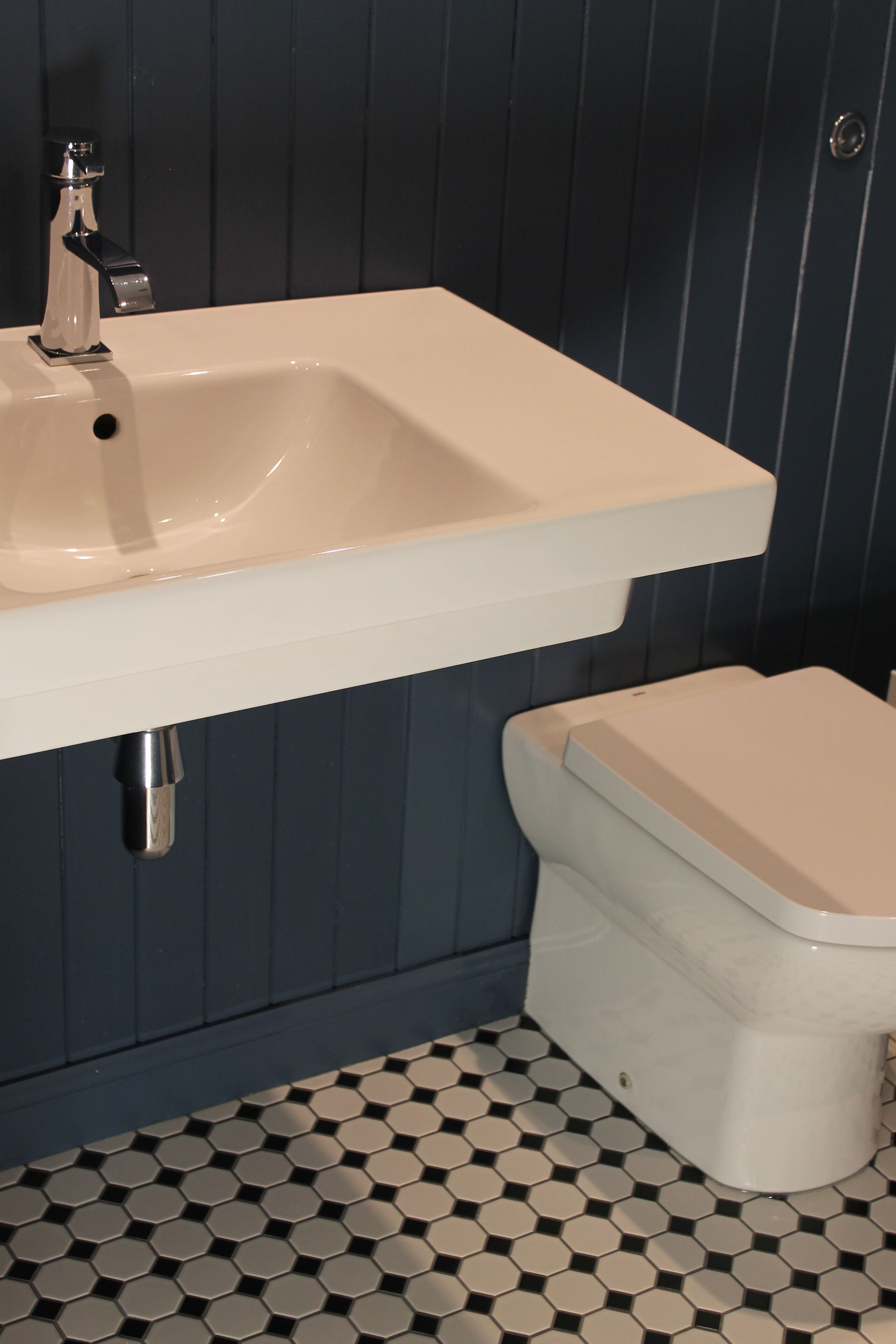 A bathroom with a white sink, a toilet, and a patterned floor.