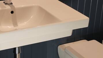 A bathroom with a white sink, a toilet, and a patterned floor.