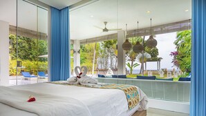 Een moderne hotelkamer met een groot bed, uitzicht op een zwembad en groen, en een plafondventilator.