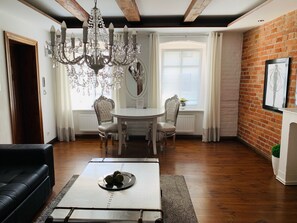 A dining area with a chandelier, a round table, and chairs. - Apartamenty Campari (Torun)