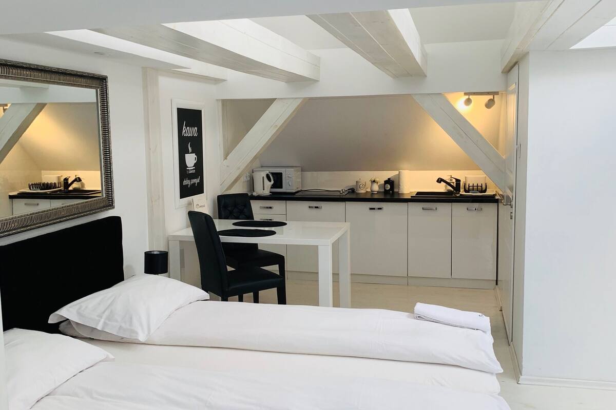 Habitación pequeña con cama, escritorio y kitchenette.
