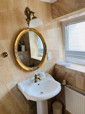 A bathroom with a gold-framed mirror, a white sink, a towel on the window sill, and a radiator. - Apartamenty Campari (Torun)
