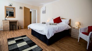 A bedroom with a bed, bedside tables, a desk, and a chair. - Spacious Family Bungalow with Garden & Annex (Laugharne)