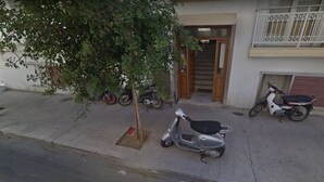 Un quartier résidentiel avec un arbre, une porte en bois et plusieurs scooters garés.