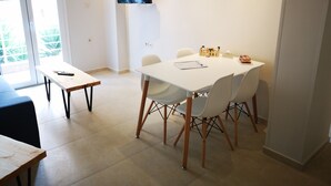 Un coin repas avec une table blanche, des chaises et un téléviseur fixé au mur.
