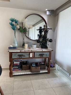 A wooden console table with a mirror above it, a vase with dried flowers, and a skeleton figure.
