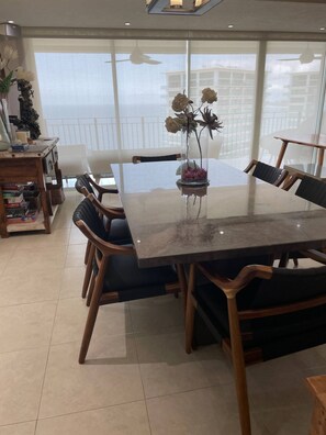 A dining area with a large table, chairs, and a vase with flowers.