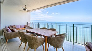 Un balcon agrémenté de meubles en osier, d’une table en bois et d’un ventilateur de plafond.
