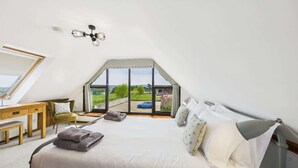 A bedroom with a large window, a bed, a desk, and a chair. - Tithe Barn, Little Upton Farm (Ashey)