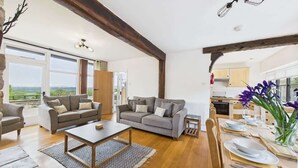 A spacious living area with two sofas, a coffee table, and a dining table set for four. - Tithe Barn, Little Upton Farm (Ashey)