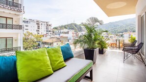 Un balcon avec un canapé, des chaises et des plantes en pot.