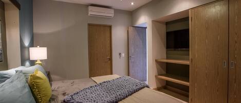Quarto com cama, ventoinha no teto, aparelho de ar condicionado, guarda-roupa e abajur.