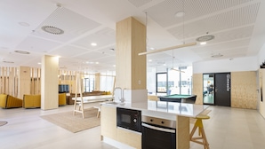 A modern kitchen with a central island, built-in appliances, and a seating area with yellow cushions. - Residencia Universitaria Resa Campus Málaga (Málaga)