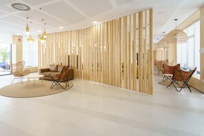 Un interior moderno con un separador de madera curvada, un sofá y dos zonas de comedor con sillas.