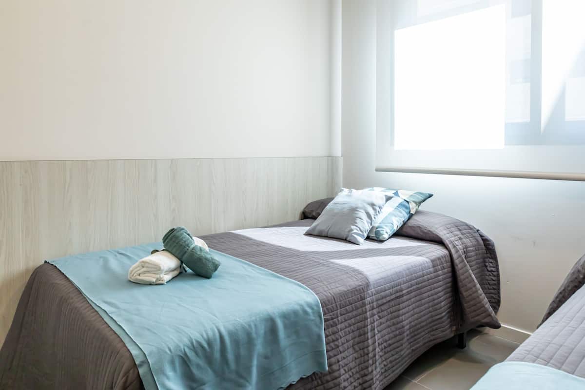 A hotel room with two beds, a window, and a wooden headboard.